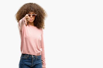 Canvas Print - African american woman wearing pink sunglasses looking unhappy and angry showing rejection and negative with thumbs down gesture. Bad expression.