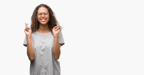 Canvas Print - Beautiful young hispanic woman wearing glasses smiling crossing fingers with hope and eyes closed. Luck and superstitious concept.