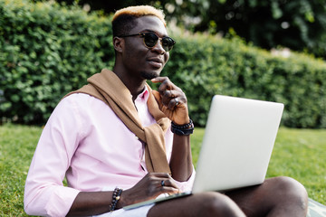 Portrait of african american man sitting outside with laptop