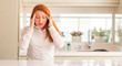 © Krakenimages.com - Redhead woman at kitchen with hand on head for pain in head because stress. Suffering migraine.