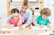 © Seventyfour - Young mother teaching her children to write an alphabet