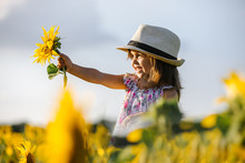 Happy Little Girl On The Field Of Sunflowers In Summer. Beautiful Little Girl In Sunflowers