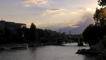A View Of The Seine In Paris, France At An Early, Pink Sunset With A Glimpse Of The Top Of The Eiffel Tower In The Horizon. The God Rays From The Sun Can Be Seen Shining Through The Clouds.