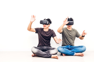 Wall Mural - Two friend sitting and having fun with technology virtual reality together on white wall background