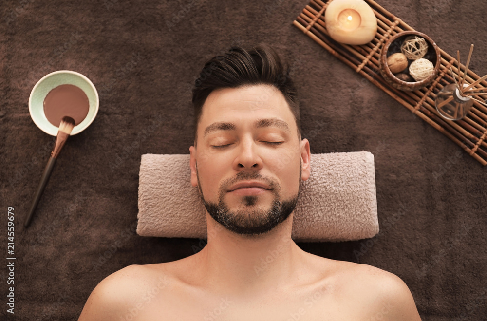 Young man relaxing on massage table in spa salon