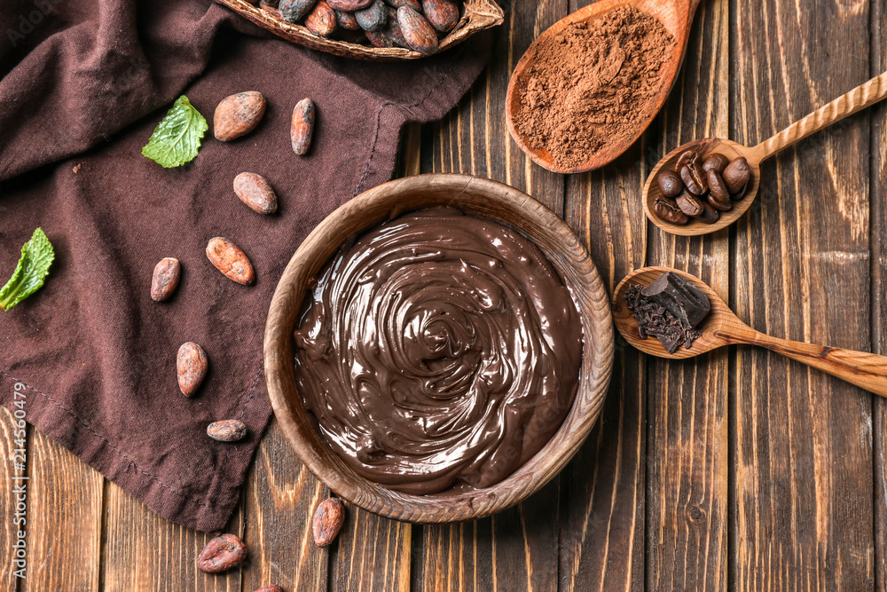 Composition with bowl of molten chocolate on wooden table