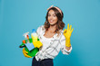 Photo of caucasian pretty housemaid 20s wearing yellow rubber gloves for hands protection holding bucket with cleaning supplies, isolated over blue background