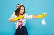 Image closeup of young funny woman 20s in yellow rubber gloves for hands protection holding two detergent sprayers during cleaning, isolated over blue background
