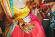 The hand with mehndi of Indian bride holding a lot of glitter bracelets (bangle) with red legenha background, close-up