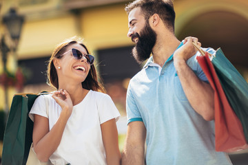 Beautiful couple enjoy shopping together, young couple holding shopping bags