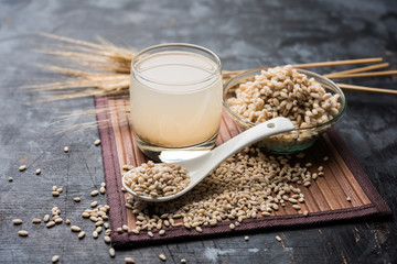 Canvas Print - Barley water in glass with raw and cooked pearl barley wheat/seeds. selective focus