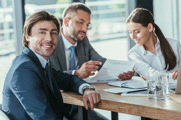 handsome businessman looking at camera during meeting at modern office