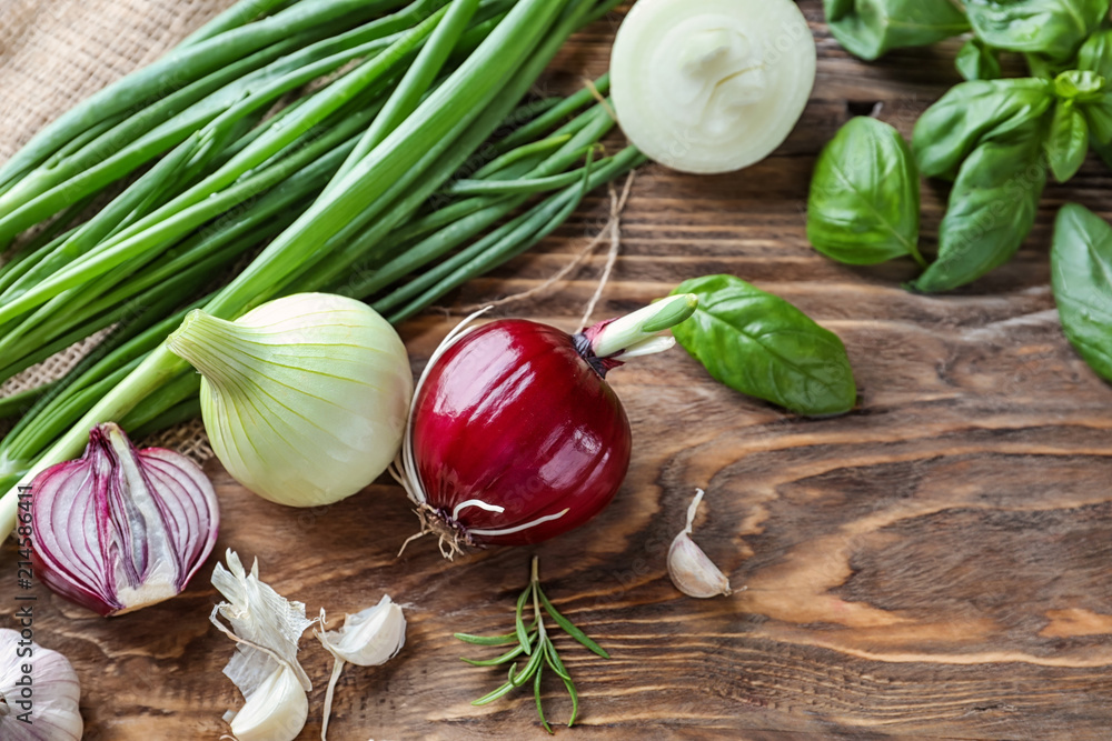 Fresh onions, basil and garlic on wooden background