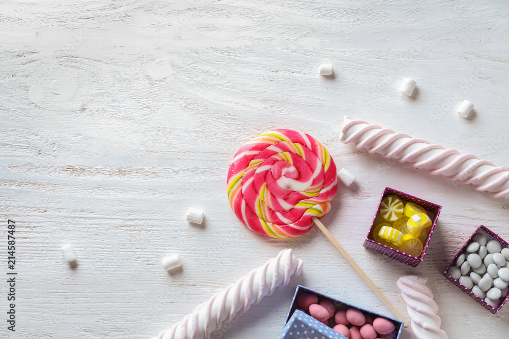 Colorful candies with marshmallows on light wooden background