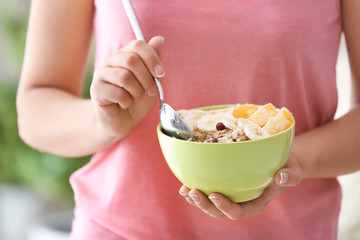 Young woman with bowl of tasty oatmeal, closeup