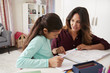 © Monkey Business - Mother Helping Daughter With Homework Sitting At Desk In Bedroom