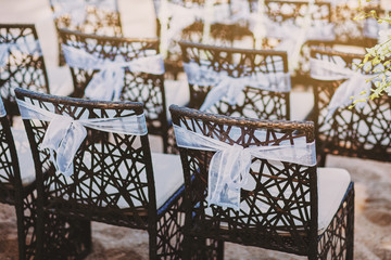 Wall Mural - The back side of black wooden chairs with white organza sash decoration for beach wedding venue