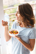 Cheerful young woman eating healthy breakfast