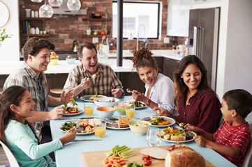 Multi Generation Family Enjoying Meal Around Table At Home Together