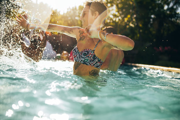 Wall Mural - Woman having fun with friends in swimming pool