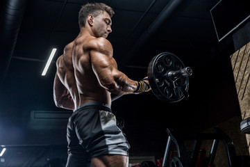 a young brutal male athlete is a bodybuilder with a perfect abs, exercising in the gym. concept - st
