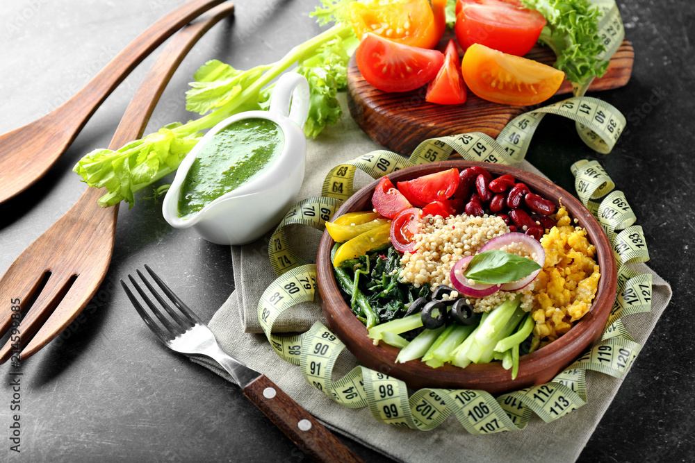 Plate with tasty quinoa salad and measuring tape on table. Diet concept
