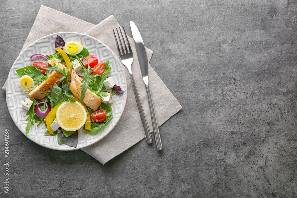 Plate with tasty chicken salad on grey table
