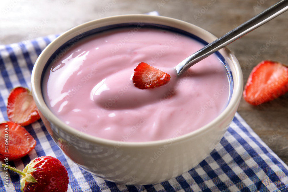 Bowl with yogurt and strawberries on table