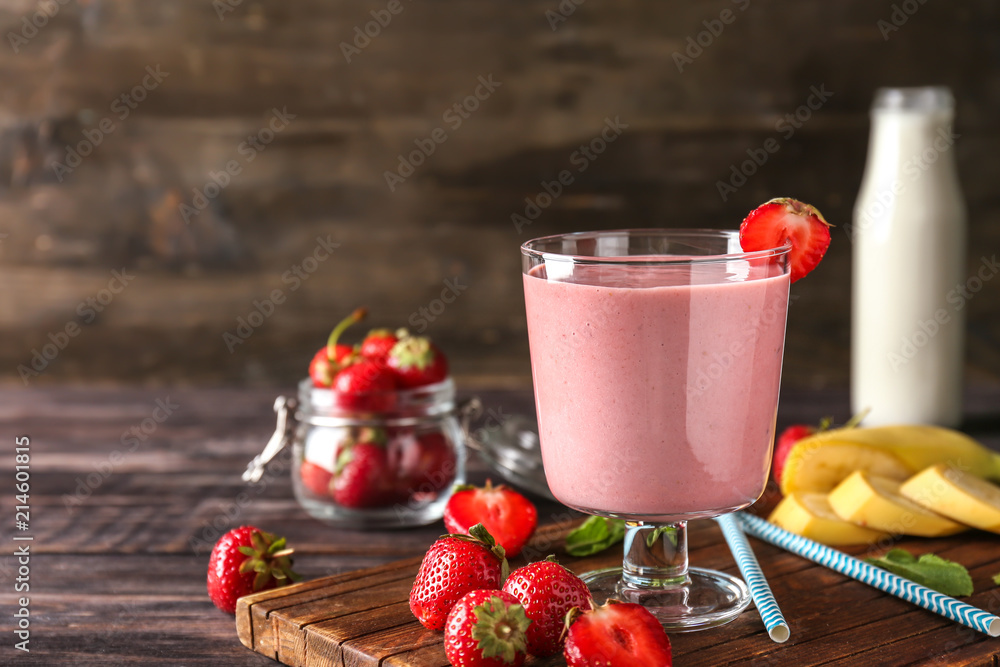 Glass with tasty strawberry smoothie on wooden table