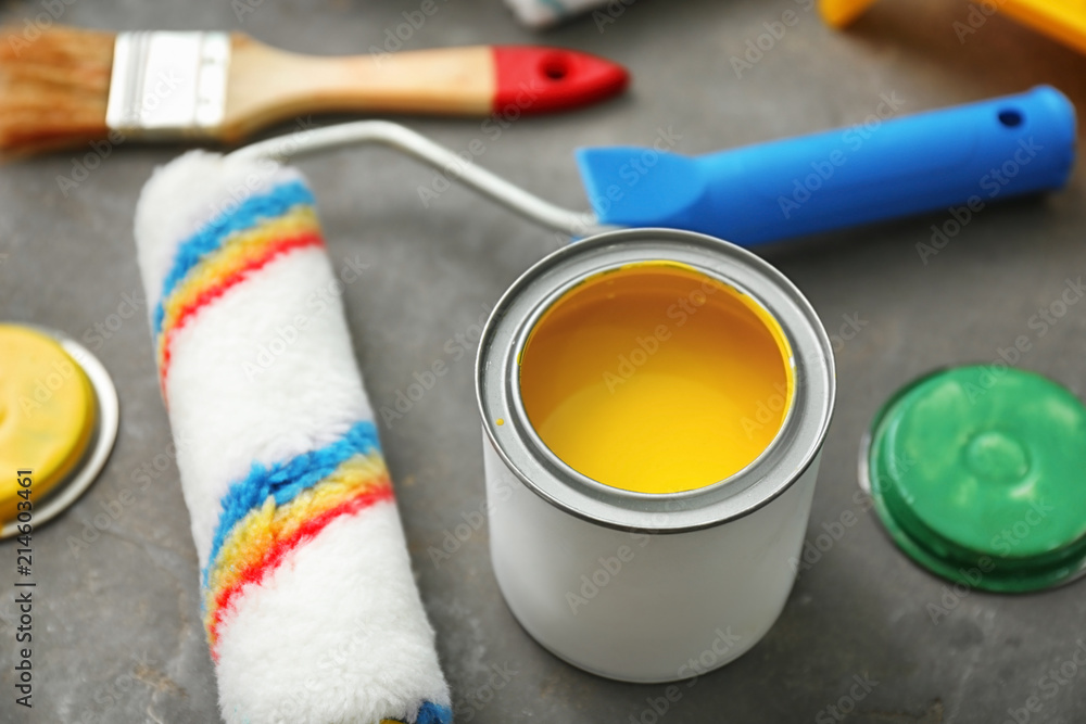 Can of paint and roller on grey background