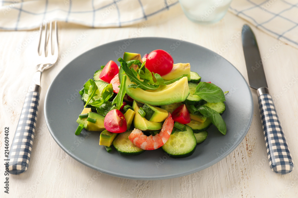 Plate with tasty avocado salad on table