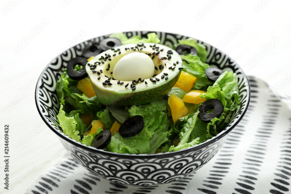 Bowl with tasty avocado salad on table