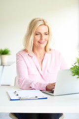 Wall Mural - Beautiful elderly woman sitting in front of laptop and working from home. Home office.