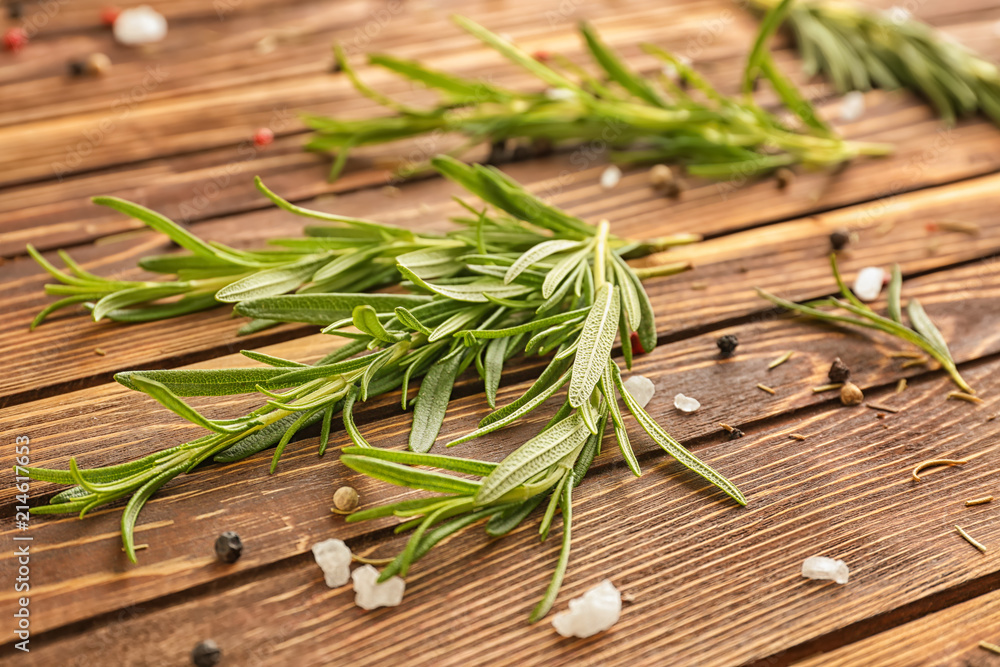 Fresh rosemary and spices on wooden background