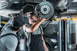 © LIGHTFIELD STUDIOS - auto mechanics repairing car without wheel in workshop