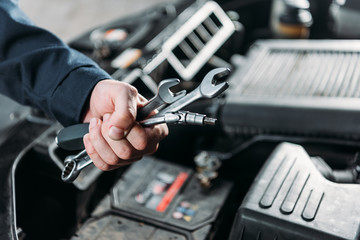 cropped view of mechanic holding wrenches in hand