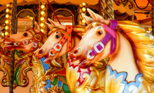 Close Up Of Three Hand Painted Carousel Horses Or Gallopers On A Fairground Ride In An Amusement Park
