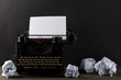 Vintage typewriter with empty, blank sheet of paper and crumbled paper balls on wood table