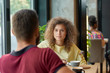 © serhiibobyk - Young couple having conversation while drinking coffee in cafe. Eating cakes, spending good time together. Curly girl wearing yellow blouse, male model having beard, burgundy polo shirt. Loft design.