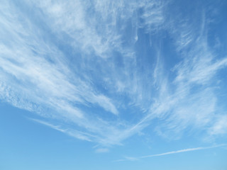 Blue sky with white feathery clouds in sunny day. Cirrus clouds as beautiful weather background