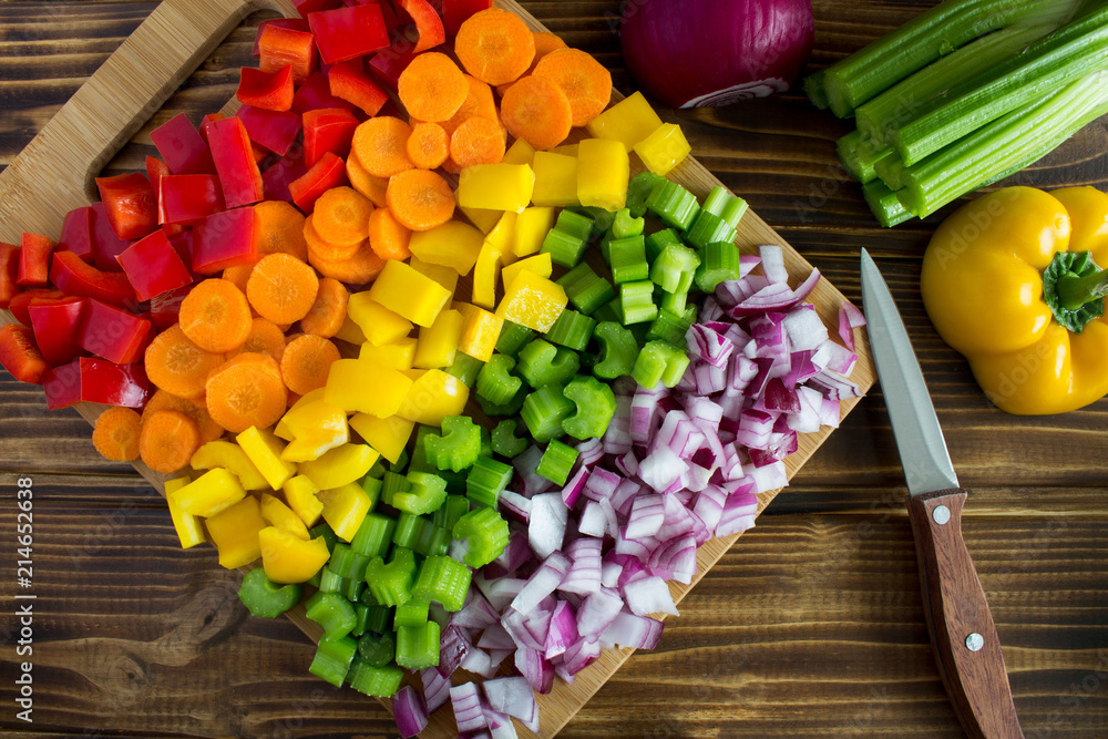 Chopped fresh vegetables  on the cutting board on the brown wooden background.Top view.