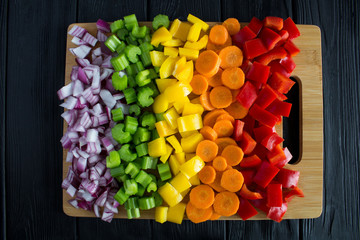 Wall Mural - Chopped fresh vegetables  on the cutting board on the black wooden background.Top view.