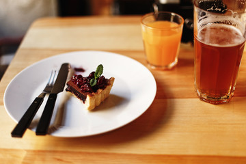 Wall Mural - delicious tasty piece of chocolate tart with cherries and mint on plate on rustic wooden table in cafe