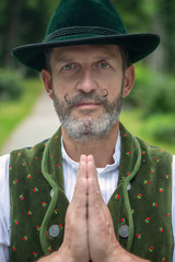 Wall Mural - bavarian man standing outdoors and praying