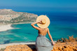 Young redhead girl in hat and dress with sea coastline on Balos, Crete, Greece