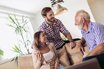 Young couple talking with their senior father at home