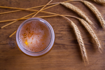 Wall Mural - Glass of beer, ears of barley on wooden table. Ale. View from above, top studio shot