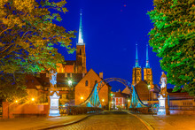 Night View Of Church Of The Holy Cross And St Bartholomew And Cathedral Of Saint John The Baptist Through A Steel Bridge In Wroclaw, Poland