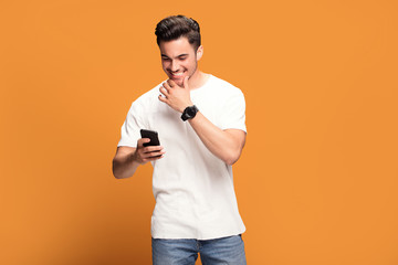 smiling handsome man with mobile phone on yellow background.