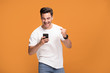 © neonshot - Smiling handsome man with mobile phone on yellow background.